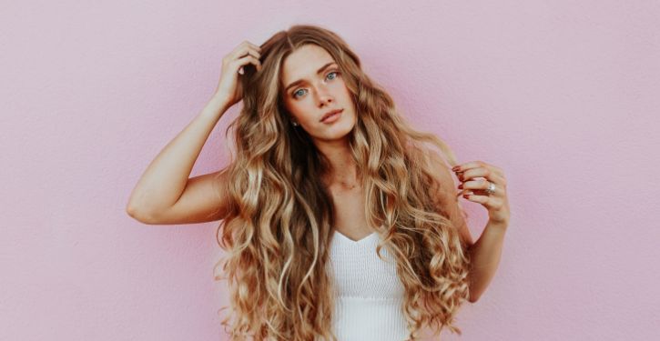woman using unscented dry shampoo to treat her long thick brown hair