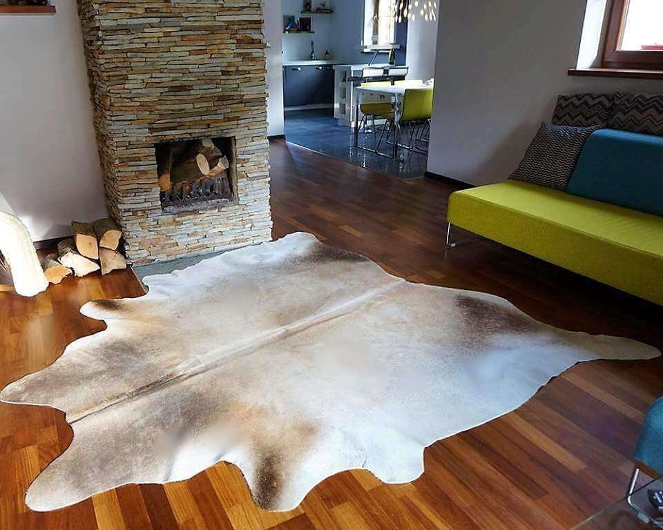 tan cowhide rug on hardwood floor next to fireplace